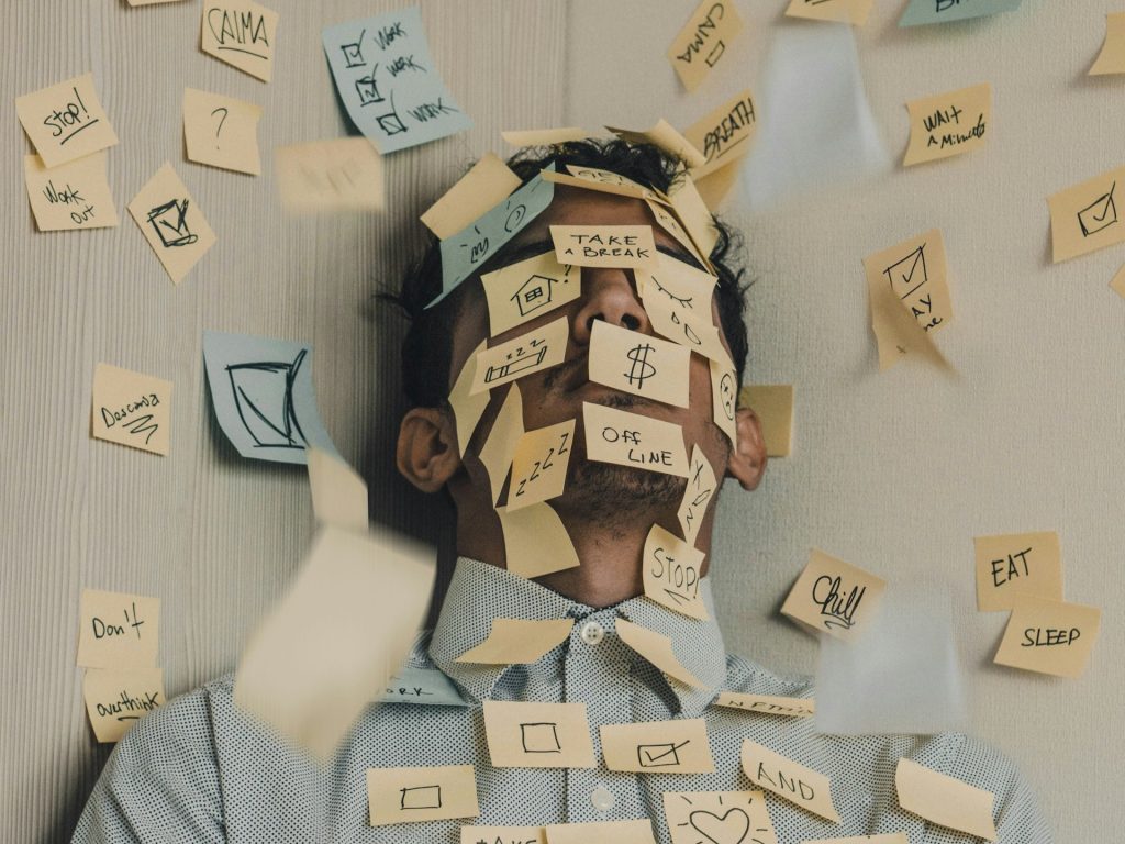 man inundated with sticky notes and tired by luis-villasmil-from-unsplash